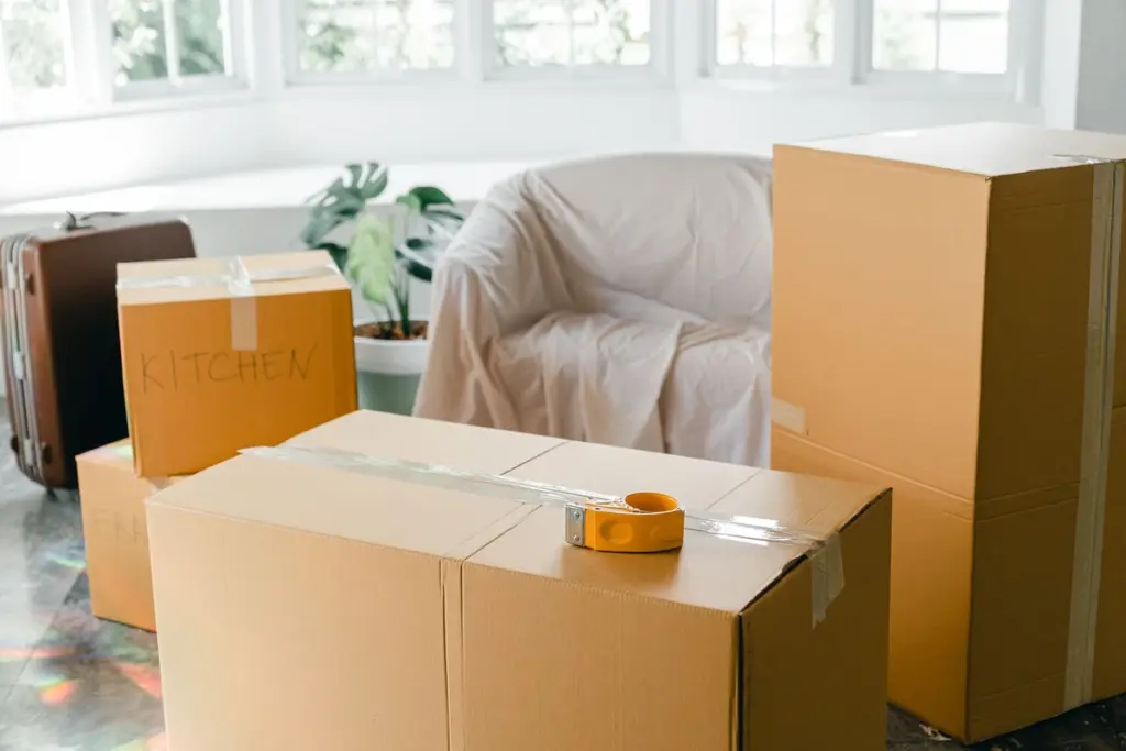 Cajas de cartón precintadas y un sillón tapado con una sábana en una casa que se está vaciando