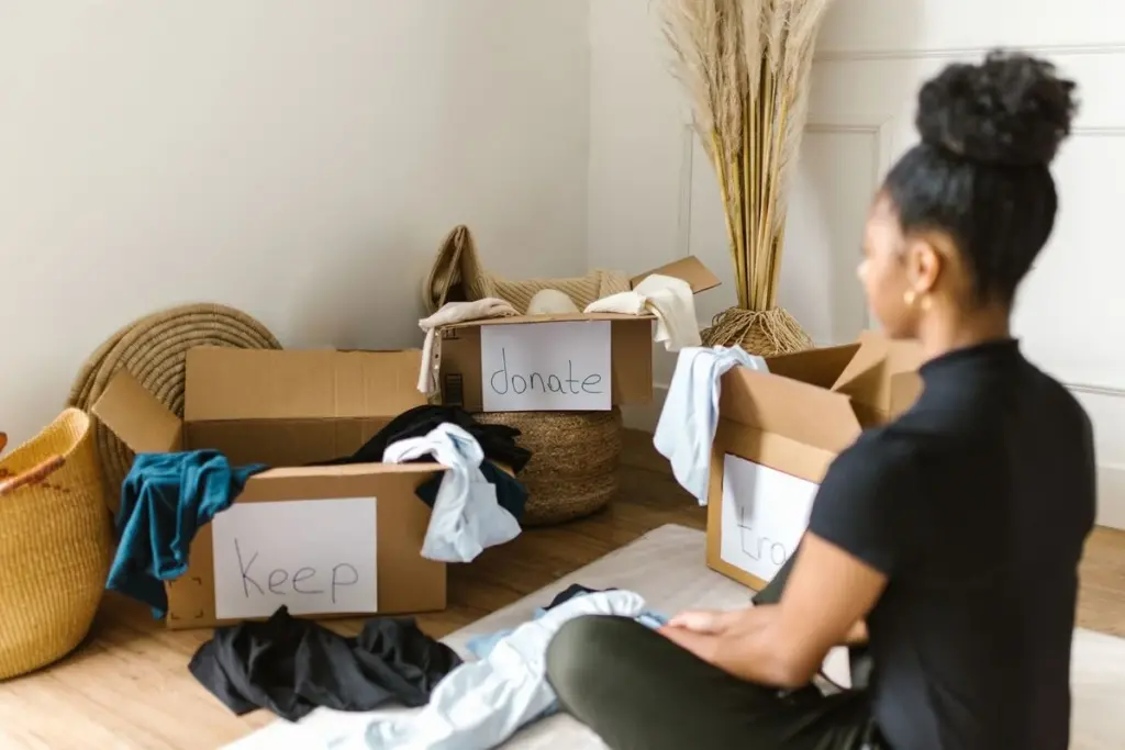 Mujer clasificando ropa en cajas para guardar, donar o tirar