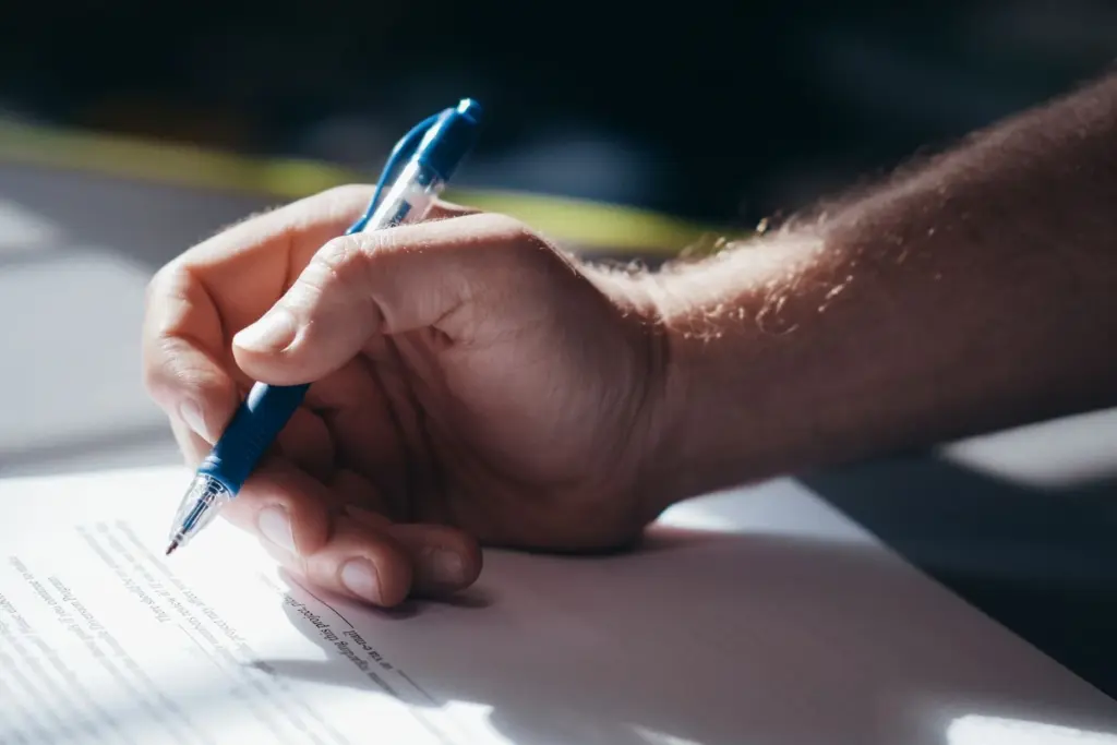 Mano firmando un documento con bolígrafo durante los trámites de una herencia