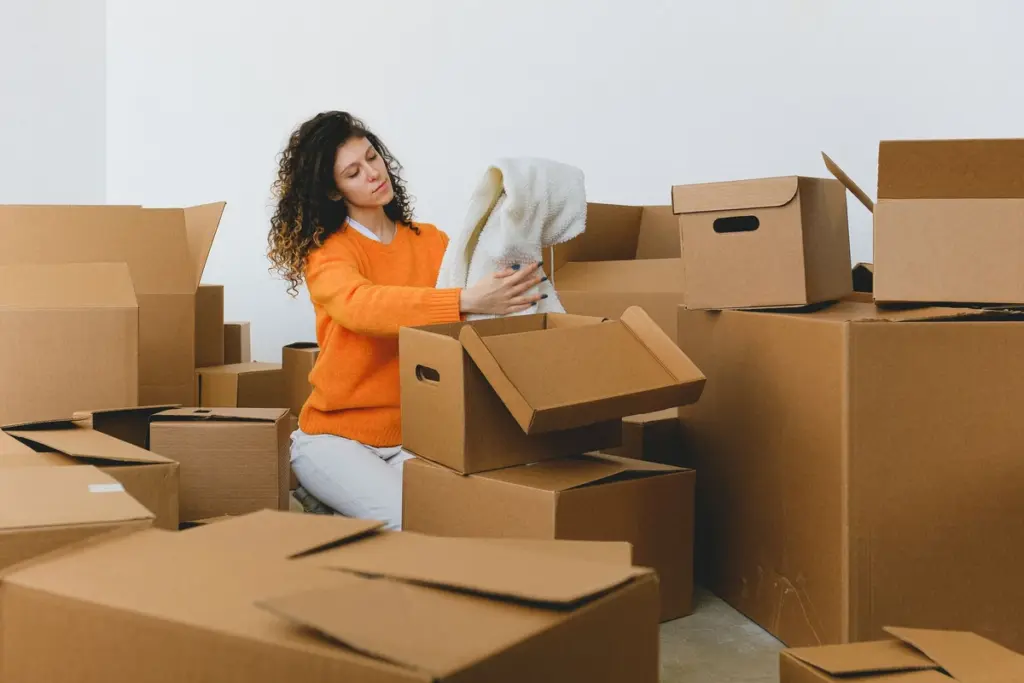 Mujer clasificando ropa en cajas de cartón al vaciar una casa