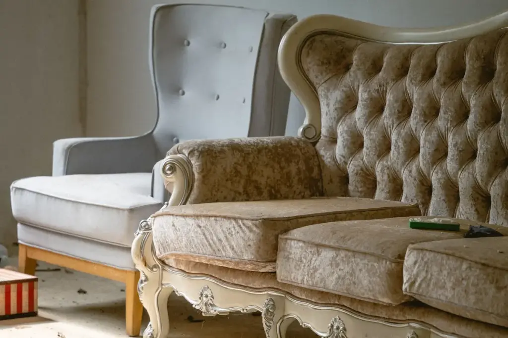 Sofá capitoné y butaca antiguos en el salón de una casa vieja